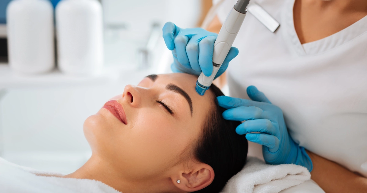 Close-up of a woman receiving a Hydrafacial in Chattanooga, TN with a clinician using a handheld device on her forehead.